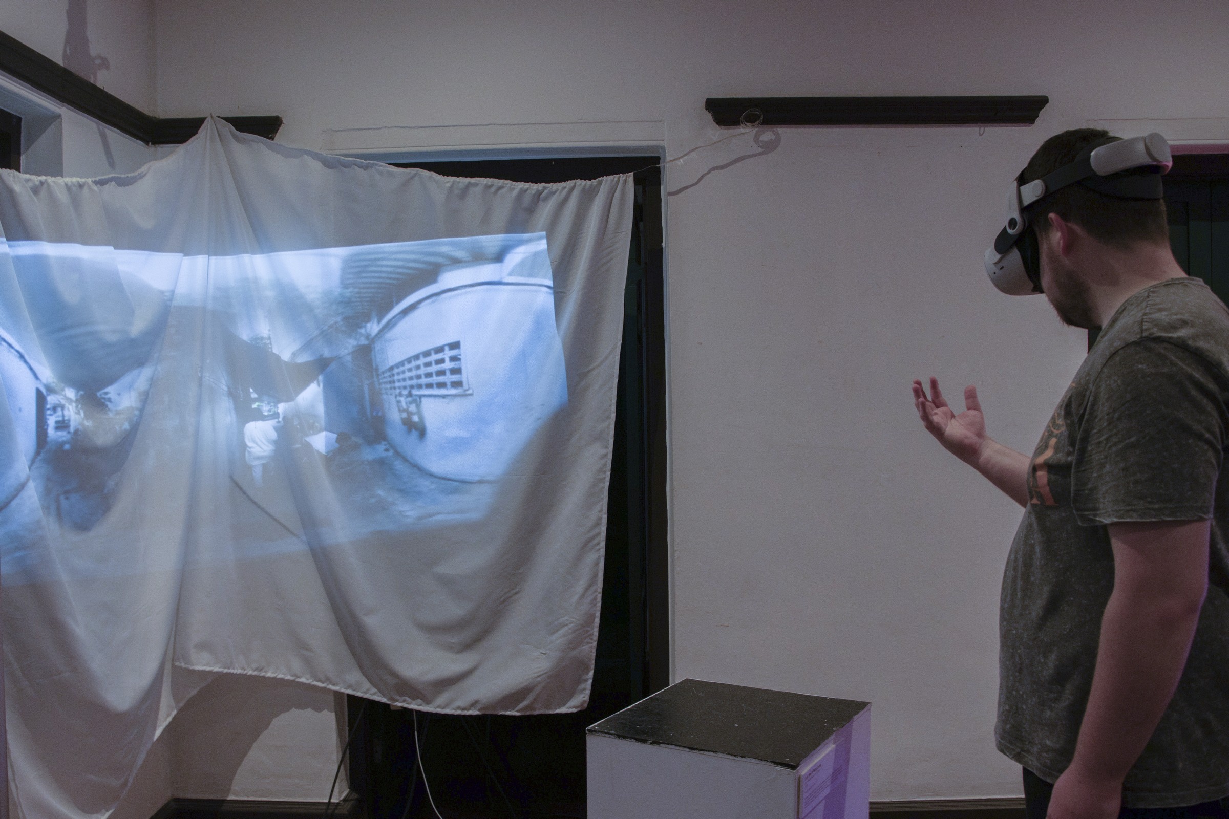 A visitor experiences Lost Time in Nang Loeng through a VR headset beside a fabric projection